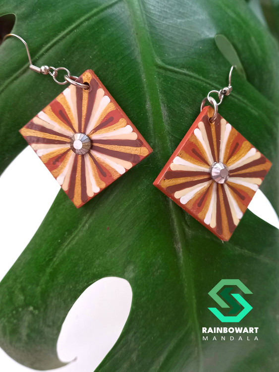 گوشوارههای چوبی مربعی رنگ قهوهای روشن با طراحی mandala art – عکاسی شده به سبک مینیمال روی برگ