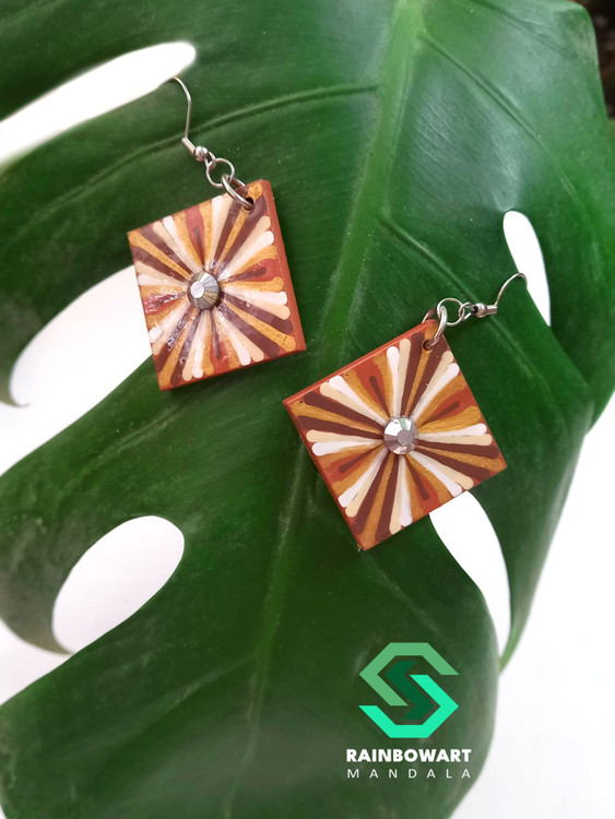 نمای دقیق از جفت گوشواره با طرح ماندالا و نقطهچینی – پسزمینه برگ گل، سبک boho chic